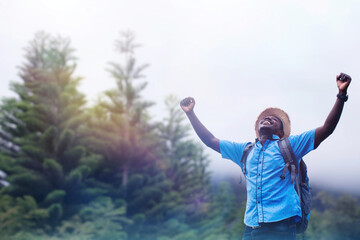 Freedom african traveler man carrying a backpack stands at the top of a mountain on a foggy day.Adventure travel and success concept