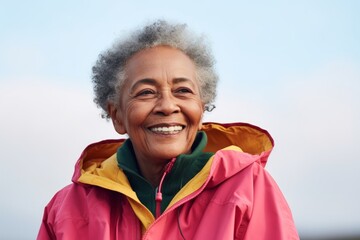 Wall Mural - Portrait of a smiling afro-american elderly woman in her 90s wearing a lightweight packable anorak on minimalist or empty room background