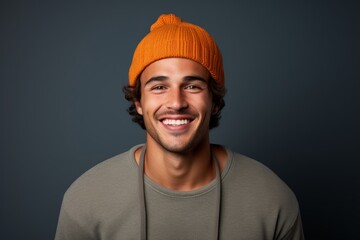 Sticker - Portrait of a smiling man in his 20s donning a warm wool beanie while standing against solid color backdrop