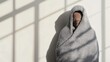 © PixelNexusArt - Person wrapped in heavy blankets despite midday sun through window, deep shadows