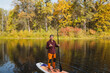 © Aleksey - A man is presently standing on a paddle board as he balances adeptly on the surface of the tranquil water, fully enjoying the stunning and picturesque natural setting that surrounds him