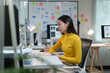 ©  NCST Studio - Young asian businesswoman taking notes while working on computer in modern office