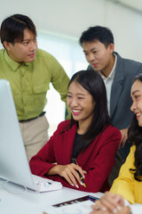 Group of young asian businesspeople analyzing data on a desktop computer, working together in a modern office