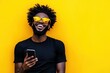 © Alfonso Soler - Portrait of handsome afro man using phone on yellow background