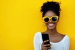 © Alfonso Soler - Portrait of handsome afro woman using phone on yellow background