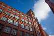 Historic red brick building under a clear blue sky and fluffy clouds. Manchester city center.