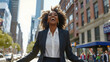 © Arvind - Happy excited confident professional young African American business woman office leader executive wearing suit celebrating financial goals standing in big city street feeling success and freedom.