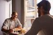 © PintoArt - Gay couple enjoying breakfast and talking at home