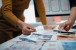 ©  NCST Studio - Web designers collaborate in an office, choosing colors for a mobile app interface, brainstorming, strategizing, and researching different color palettes