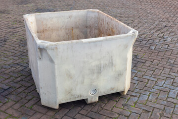 large open plastic container stands outside on the street