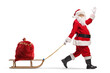 © Ljupco Smokovski - Santa Claus pulling a wooden sled with a sack and waving
