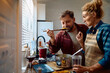 © Drazen - Smiling man tasting food cooked by his wife in kitchen.