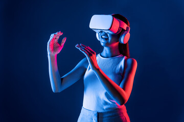 Smart Female standing surrounded by neon light wear VR headset connecting metaverse, futuristic cyberspace community technology, using both hands interact with generated virtual object. Hallucination.