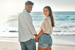 © peopleimages.com - Portrait, honeymoon or happy couple at sea holding hands for love on vacation, anniversary or holiday. Smile, trust or people at beach for bonding together for travel or ocean trip adventure in Spain