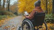 © Emiliia - Person in a wheelchair using a mobile app on a fall day in a park surrounded by colorful leaves