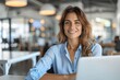 © zong - Professional Mature Business Woman in Blue Shirt Smiling and Working on Laptop in Modern Office Thinking of Technology Future