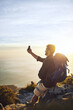© peopleimages.com - Selfie, beach and man with backpack, hiking and view with adventure, vacation and ocean. Outdoor, hiker and healthy person with cellphone, coastline and getaway trip with internet, seaside or journey