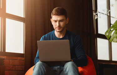 Poster - Busy Freelancer Guy Working On Laptop Sitting In Beanbag Chair At Home. Freelance Career Concept