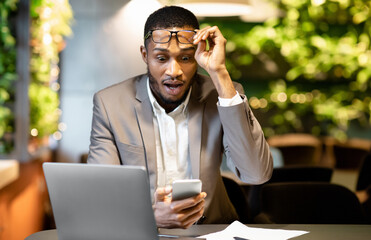 Poster - Shocking Message. Surprised black man in spectacles looking at bill receipt on smartphone, stressed about business news