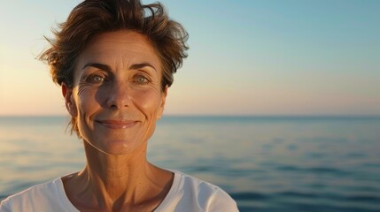 Poster - A cheerful, graceful older woman wearing a white tshirt sits by the serene sea, radiating positivity and warmth.