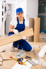 Young female repairer installing laminate flooring in apartment.