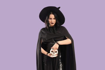 Beautiful young woman dressed as witch for Halloween with human skull on purple background