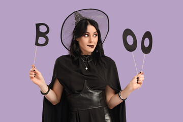 Beautiful young thoughtful woman dressed as witch for Halloween with word BOO on purple background