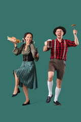 Wall Mural - Happy mature waiters in traditional German clothes with glass, mug of beer and snacks on green background