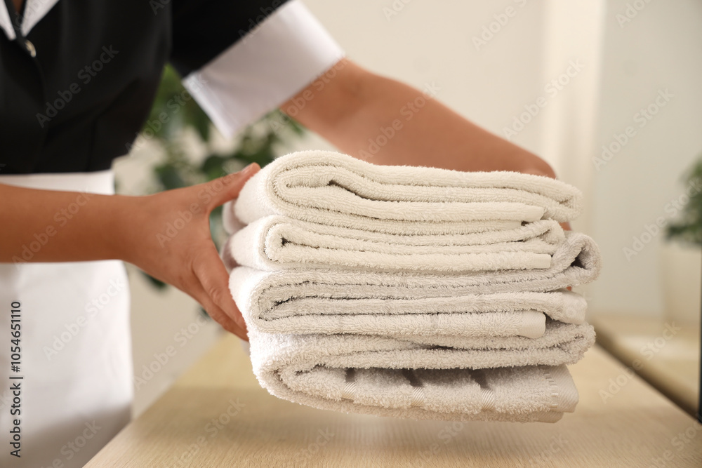 Young chambermaid with clean towels  in bathroom, closeup