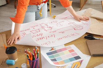 Wall Mural - Female fashion designer working with drawing at table in studio, closeup