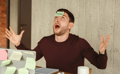Poster - Exhausted Office Worker Guy Having Sticky Notes On Face And Everywhere Sitting At Workplace Indoor. Selective Focus