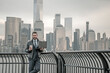 © Volodymyr - Businessman drink coffee. Businessman walk in business district at Manhattan. Businessman in a suit standing in front of a office building in New York City. Outdoor portrait of Hispanic businessman.