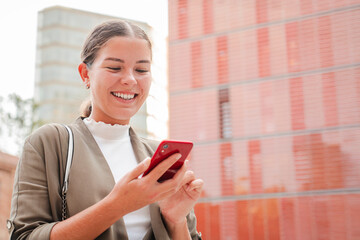 copy space. smiling young woman using a cellphone outdoors, checking messages or social media in an 