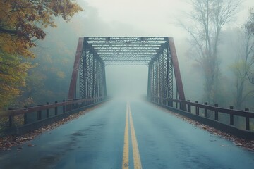 empty road crossing an old, mist-covered bridge over a calm river. The fog is thick, making it difficult to see the opposite side of the bridge