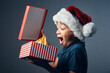 © peopleimages.com - Studio, boy and wow with Christmas gift as surprise, present and celebration on gray background. Male person, isolated and smile or excited with box for festive season, holiday and fun with joy