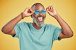 © peopleimages.com - Sunglasses, summer and fashion with black man in studio for cool, confidence and happiness. Trendy, excited and aesthetic with mature person on yellow background for hipster, creative and accessory