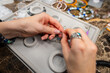 © yanik88 - Top view artistic female hands creating bracelet from stones. POV shot of woman working with craft. Accessories on workshop table close up