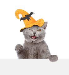 Poster - Winking happy kitten wearing hat for halloween looks above blank white banner. isolated on white background