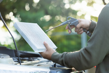 Car owner holds an air filter for examination. Importance of regular inspection, cleaning, and replacement of car air filters, Emphasizes maintenance for better air quality and vehicle efficiency