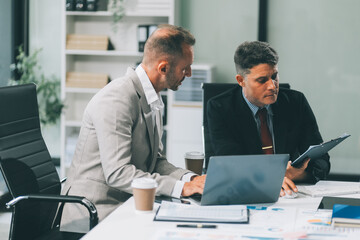 Two businessmen working together Analyze financial reports with charts and graphs while using the calculator to calculate budget, income, taxes, business growth. Startup business idea.