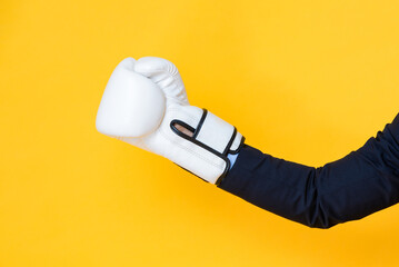 Businessman hand wearing boxing glove on yellow isolated background, business war and battle concept