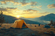 © stanhert - A tent is set up on a grassy field with a mountainous landscape in the background during sunset