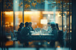 © Marek - Un grupo de empresarios sentados alrededor de una mesa en una oficina, trabajando juntos en sus proyectos. La escena está captada a través de paredes de vidrio con un fondo borroso y la luz natural