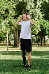 Tattooed young man with artificial leg enjoying nature and music in a sunny park