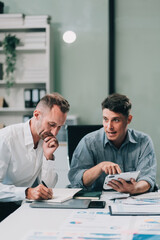 Two businessmen working together Analyze financial reports with charts and graphs while using the calculator to calculate budget, income, taxes, business growth. Startup business idea.