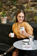 In a cozy cafe, a young woman sips her coffee while checking her phone, confidently embracing her lifestyle with a prosthetic leg.