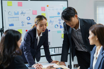 Asian businesspeople discussing and analyzing data on charts and reports in office meeting, teamwork and brainstorming concept