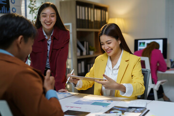 Asian businesswomen showing digital tablet to colleagues during a meeting in modern office