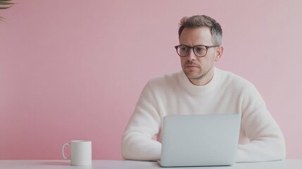 Poster - A man wearing glasses sits at a desk with a laptop and a cup of coffee
