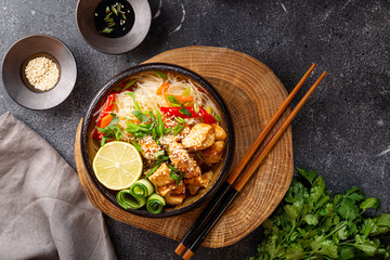 A bowl of glass or cellophane noodles with Asian caramelized chicken breast on dark grey background top view